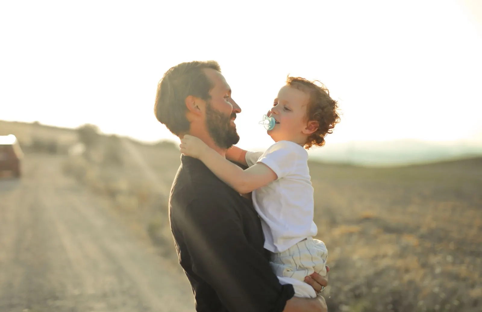 Un padre tiene in braccio il figlio piccolo al tramonto, sereno, lontano dal telefono